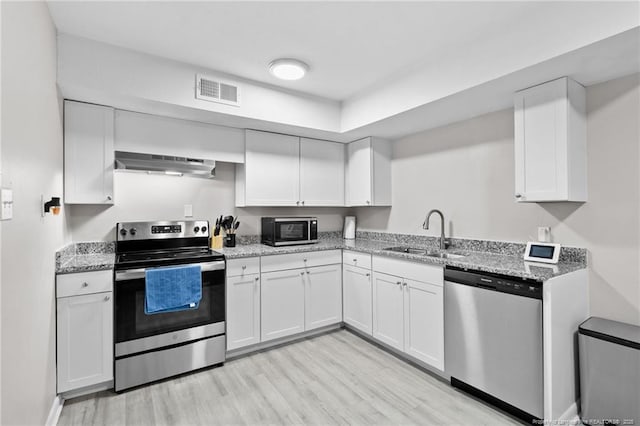 kitchen featuring white cabinetry, sink, stainless steel appliances, light stone counters, and ventilation hood