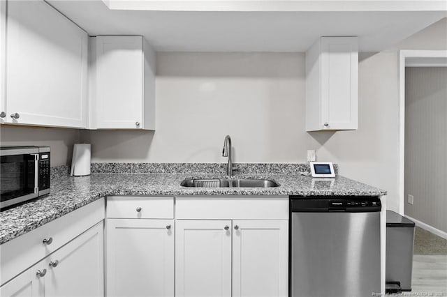 kitchen with light stone countertops, stainless steel appliances, white cabinetry, and sink