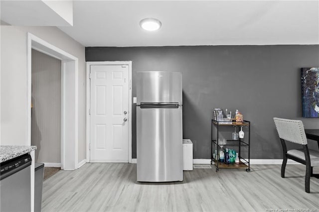 kitchen with light stone countertops, appliances with stainless steel finishes, and light hardwood / wood-style flooring