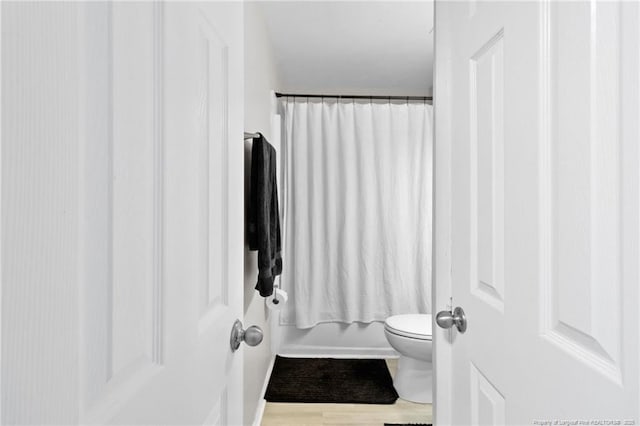 bathroom featuring shower / bathtub combination with curtain and toilet