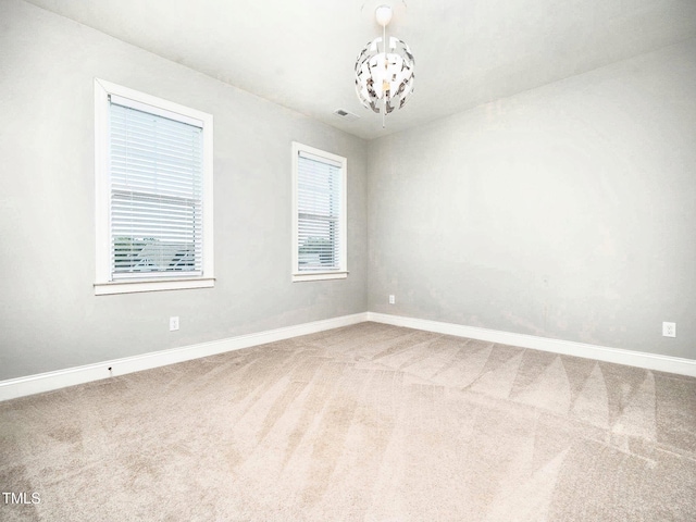 spare room featuring carpet flooring and an inviting chandelier