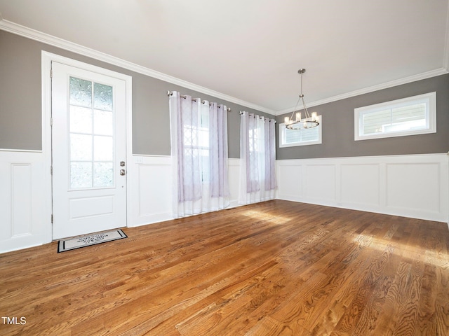 unfurnished dining area with ornamental molding, a healthy amount of sunlight, and wood-type flooring