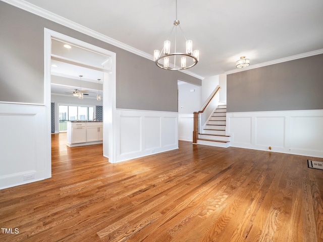 empty room featuring ceiling fan with notable chandelier, light hardwood / wood-style floors, and ornamental molding