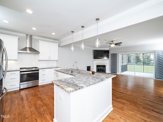 kitchen featuring appliances with stainless steel finishes, wall chimney exhaust hood, ceiling fan, sink, and white cabinetry