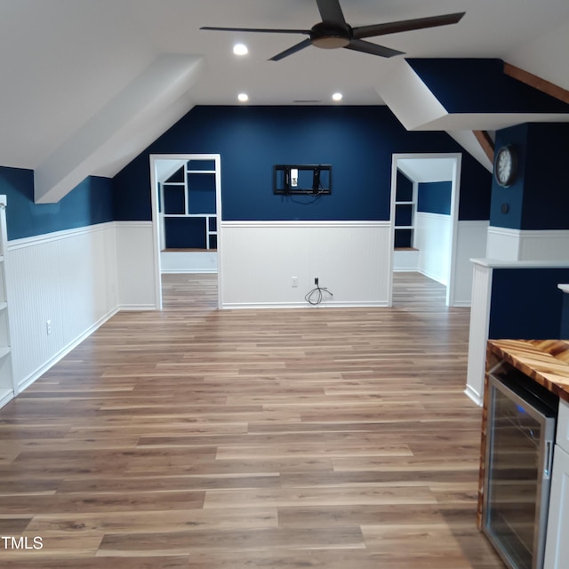 additional living space with ceiling fan, light hardwood / wood-style flooring, wine cooler, and vaulted ceiling