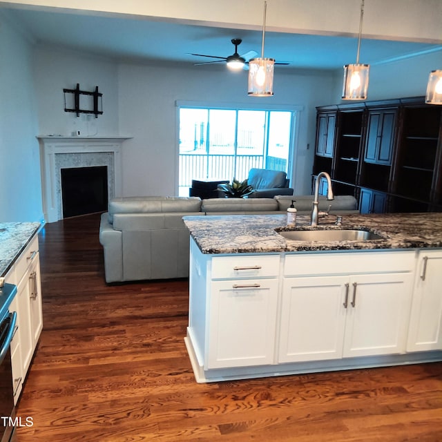 kitchen featuring dark stone countertops, sink, white cabinets, and pendant lighting