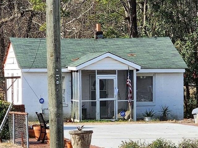 view of front of home featuring a shingled roof and a sunroom