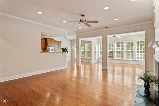unfurnished living room featuring ornamental molding, a fireplace with raised hearth, a ceiling fan, and light wood-style flooring