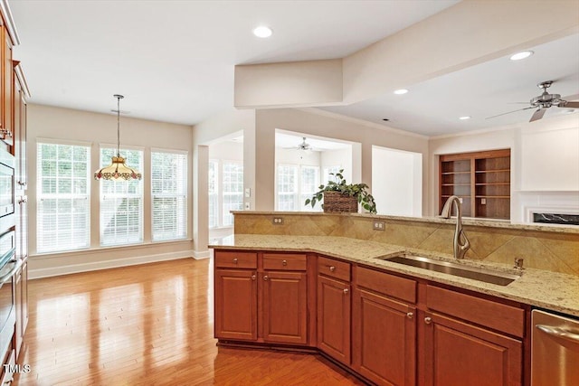 kitchen with a ceiling fan, light stone counters, a sink, and light wood-style floors