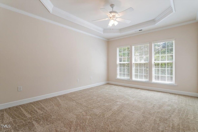 spare room with carpet flooring, a raised ceiling, a ceiling fan, visible vents, and ornamental molding