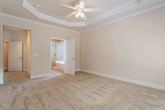 unfurnished bedroom with crown molding, baseboards, carpet, a tray ceiling, and ensuite bath