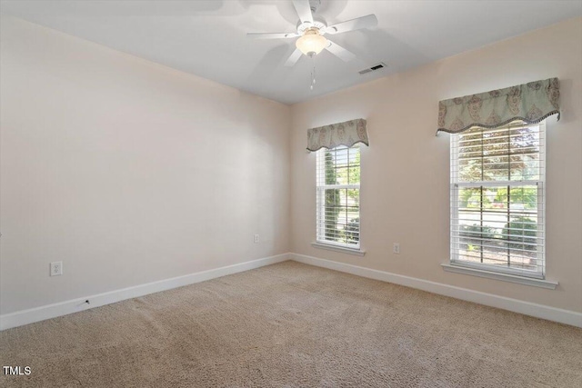 spare room featuring baseboards, ceiling fan, light colored carpet, and visible vents