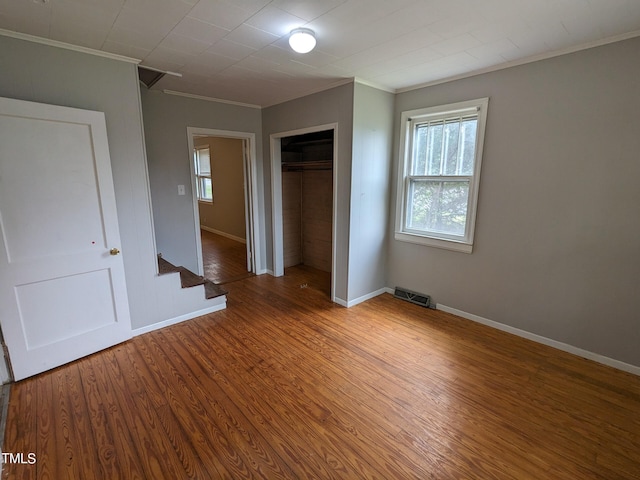 unfurnished bedroom featuring hardwood / wood-style flooring, a closet, and crown molding