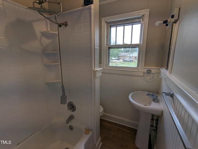 bathroom with radiator heating unit, hardwood / wood-style flooring, toilet, and tiled shower / bath