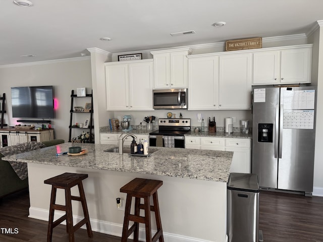 kitchen with a kitchen breakfast bar, stainless steel appliances, sink, white cabinets, and an island with sink