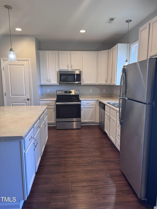 kitchen with white cabinetry, dark hardwood / wood-style flooring, decorative light fixtures, and appliances with stainless steel finishes