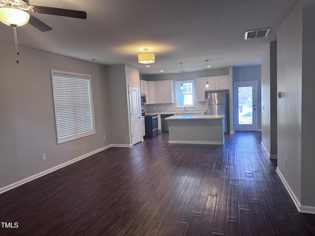 kitchen featuring pendant lighting, white cabinetry, a kitchen island, and appliances with stainless steel finishes