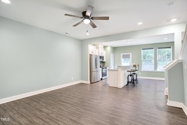 kitchen with white cabinetry, a center island, a kitchen bar, ceiling fan, and appliances with stainless steel finishes