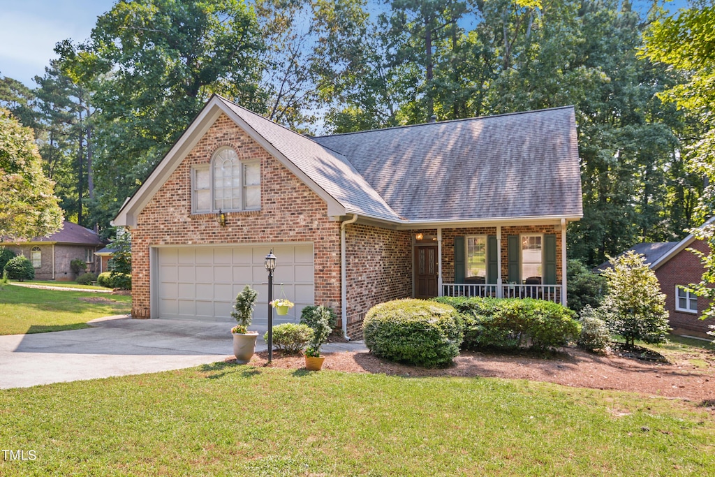 view of front of house featuring a front yard, a garage, and a porch