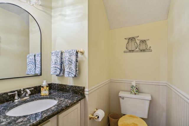 bathroom with toilet, lofted ceiling, and vanity