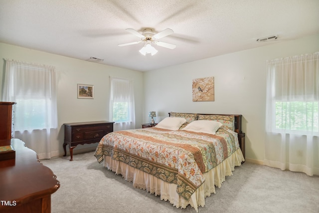 carpeted bedroom with ceiling fan and a textured ceiling