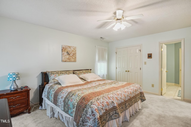 bedroom featuring light carpet, a textured ceiling, a closet, and ceiling fan