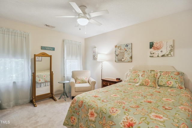 bedroom featuring ceiling fan, light colored carpet, and a textured ceiling