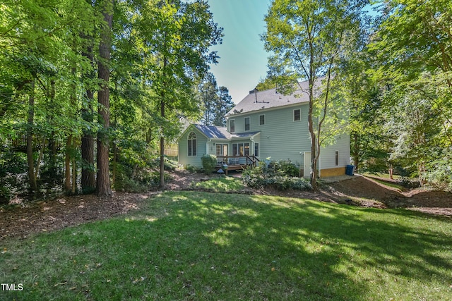 rear view of house featuring a wooden deck and a yard