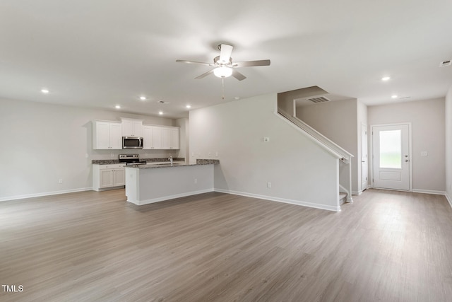 unfurnished living room featuring ceiling fan, light hardwood / wood-style floors, and sink