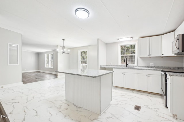 kitchen featuring decorative light fixtures, a notable chandelier, white cabinets, a center island, and range with electric stovetop