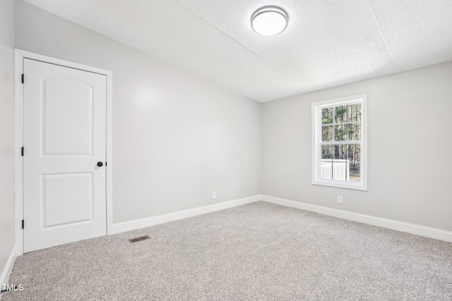 carpeted empty room featuring a textured ceiling