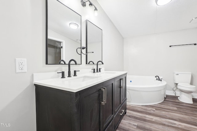 bathroom featuring a bathing tub, wood-type flooring, lofted ceiling, toilet, and vanity