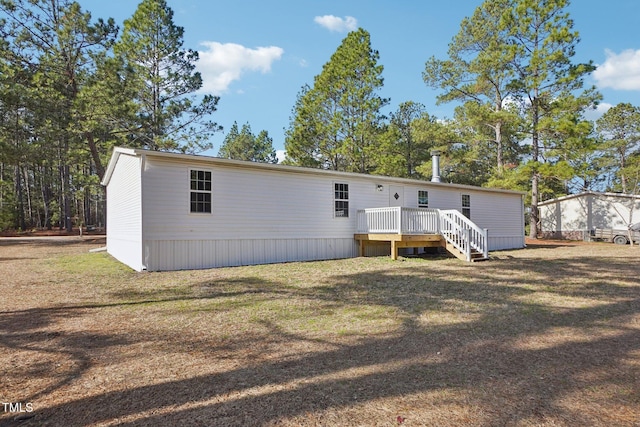 rear view of house featuring a lawn and a wooden deck