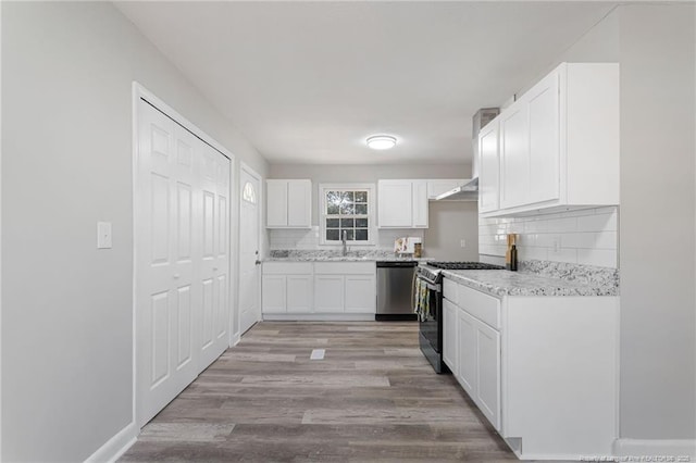 kitchen featuring light hardwood / wood-style flooring, ventilation hood, decorative backsplash, white cabinets, and appliances with stainless steel finishes