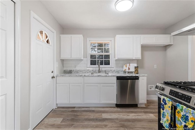 kitchen with light stone countertops, backsplash, stainless steel appliances, sink, and white cabinets