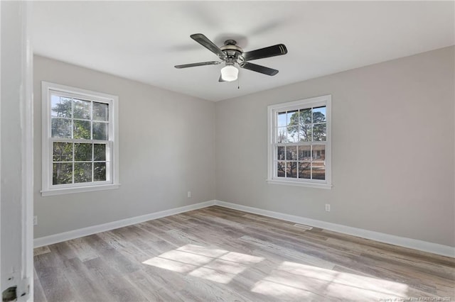 empty room with ceiling fan, plenty of natural light, and light hardwood / wood-style flooring