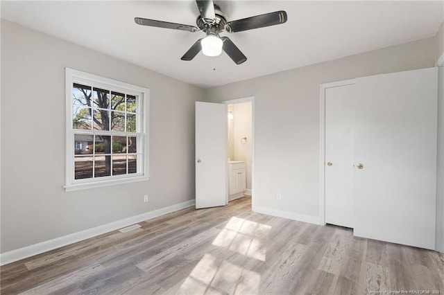 unfurnished bedroom featuring ceiling fan, light hardwood / wood-style floors, ensuite bathroom, and a closet