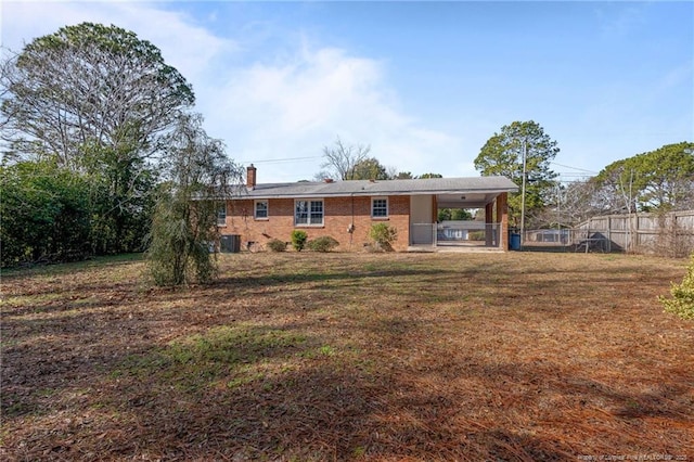 back of house featuring a lawn, a carport, and central air condition unit