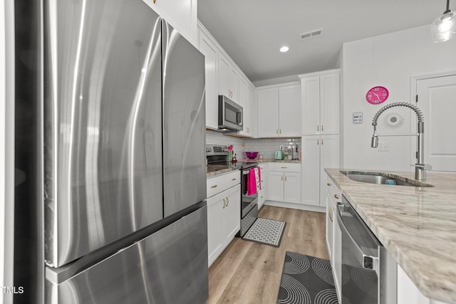 kitchen with hanging light fixtures, white cabinetry, sink, and appliances with stainless steel finishes