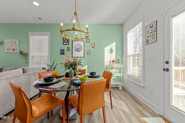 dining area with light wood-type flooring and a notable chandelier