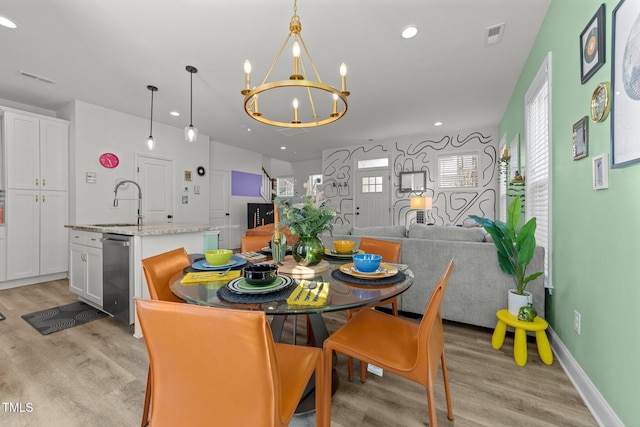 dining room with light hardwood / wood-style floors, sink, and an inviting chandelier