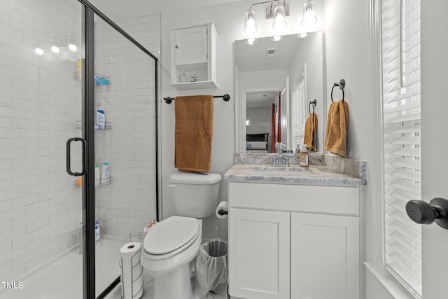 bathroom featuring vanity, a shower with shower door, and toilet