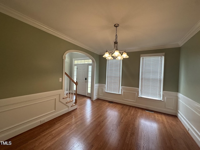 empty room with crown molding, hardwood / wood-style floors, a healthy amount of sunlight, and a notable chandelier