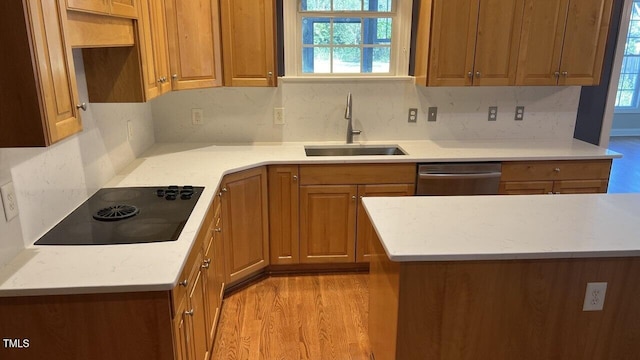 kitchen featuring black electric stovetop, sink, stainless steel dishwasher, decorative backsplash, and light hardwood / wood-style floors