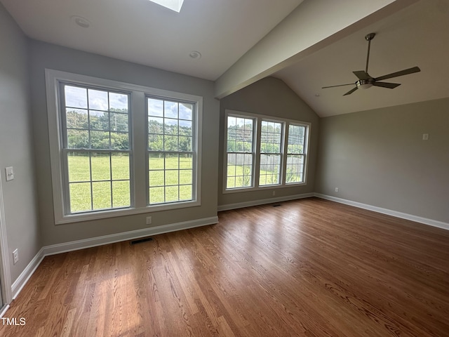 unfurnished room with dark hardwood / wood-style flooring, ceiling fan, and vaulted ceiling with skylight