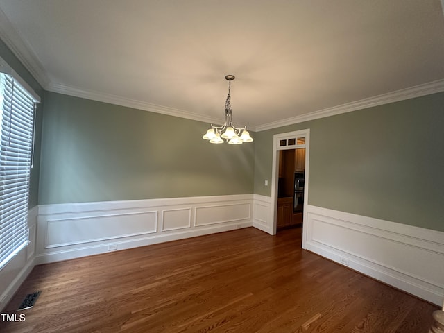 empty room with a chandelier, dark hardwood / wood-style flooring, and ornamental molding