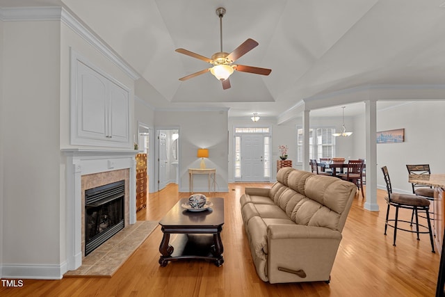 living room with a tile fireplace, ceiling fan, light hardwood / wood-style floors, and vaulted ceiling