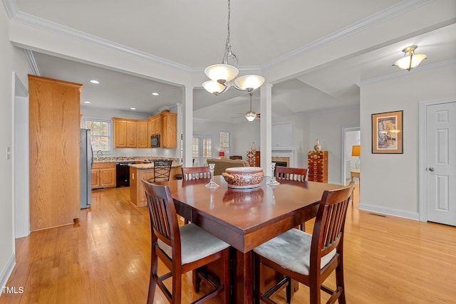 dining room with crown molding, sink, ceiling fan with notable chandelier, and light wood-type flooring