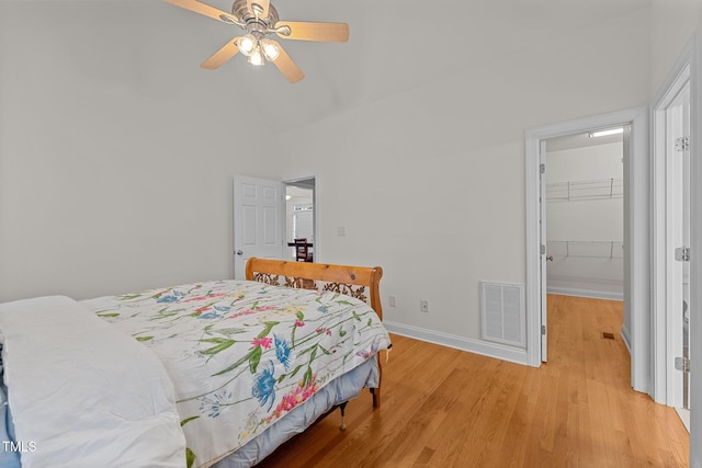 bedroom with ceiling fan, a spacious closet, light hardwood / wood-style flooring, high vaulted ceiling, and a closet