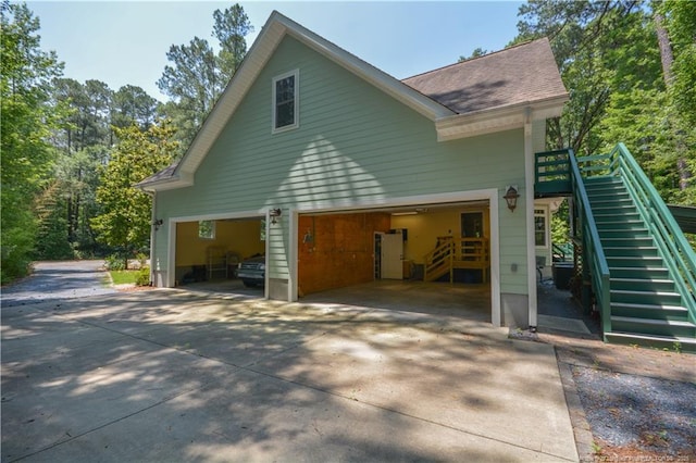 654 Titmouse Ct, Vass, NC 28394 - view of property exterior featuring stairway, a garage, roof with shingles, and driveway